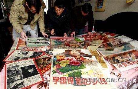 3月1日，房冠龍（中）在家中整理關于雷鋒的宣傳海報。